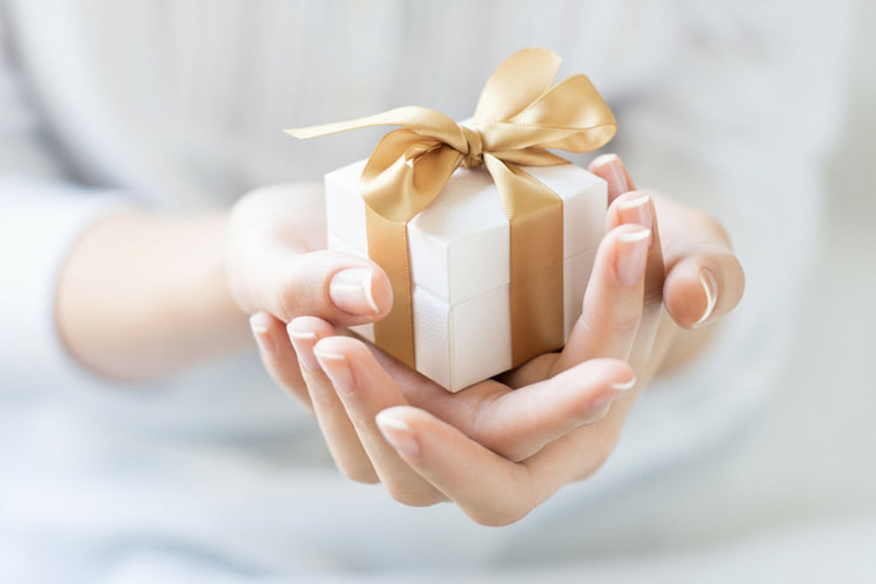Small gift box with a pink ribbon held in hands against a light background